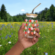 Load image into Gallery viewer, Hand holding a glass with strawberry design in front of a field with wildflowers