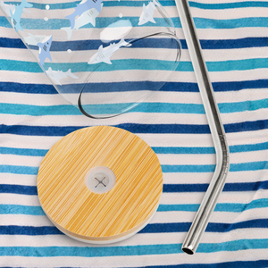 Glass with shark design on top of a blue striped beach towel