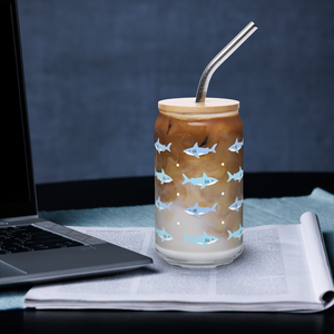 Glass with shark design filled with iced coffee on a desk with a laptop