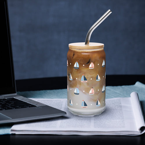 Glass with sailboat design filled with iced coffee next to a laptop